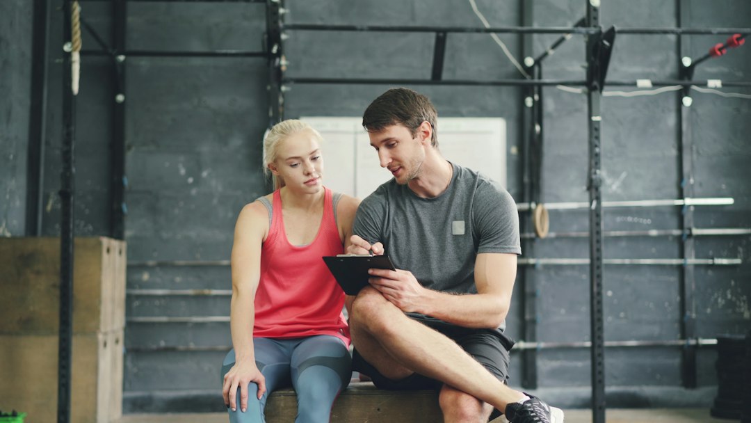 A fitness professional reviewing a training plan with a client on a tablet